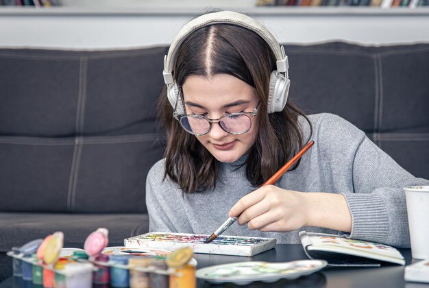 Een stijlvolle jonge vrouw tekent met verf in het interieur