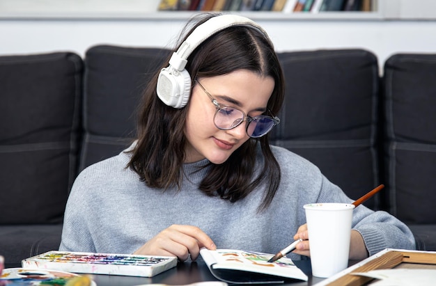 Een stijlvolle jonge vrouw tekent met verf in het interieur