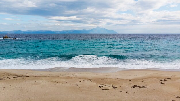 Een strand met blauwe golven van de Egeïsche zee en de bergen