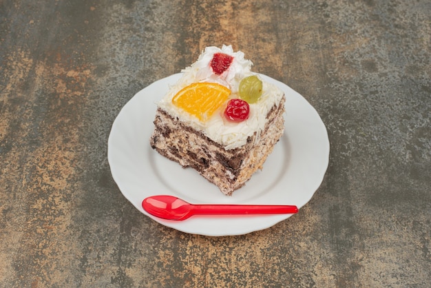 Een stukje zoete cake met rode lepel op een witte plaat