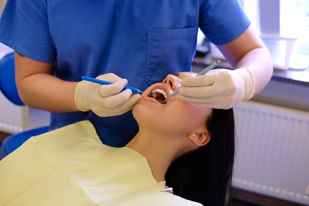 Een tandarts werkt aan jonge vrouwenpatiënt met tandhulpmiddelen.