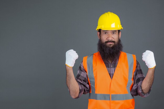 Een technische man met een gele helm met witte handschoenen toonde een grijs gebaar.