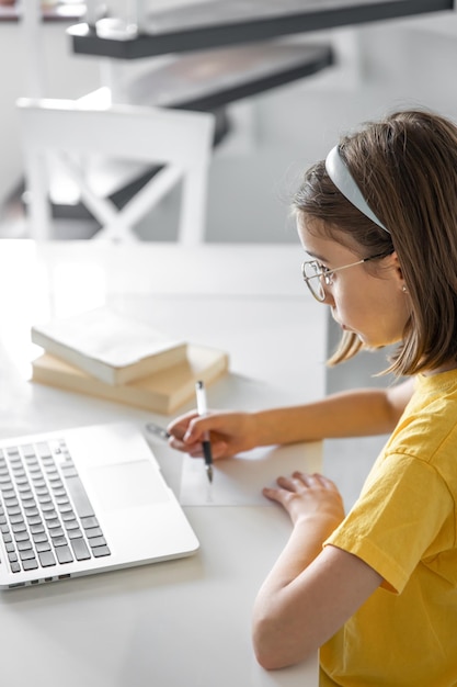 Gratis foto een tienermeisje doet haar huiswerk terwijl ze met boeken en een laptop zit
