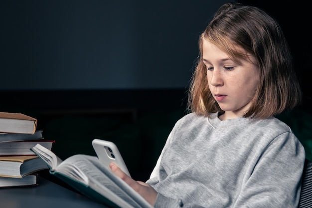 Een tienermeisje gebruikt een smartphone in plaats van een boek te lezen