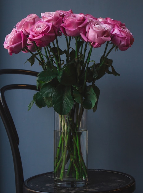 Een vaas met water en roze rozen erin