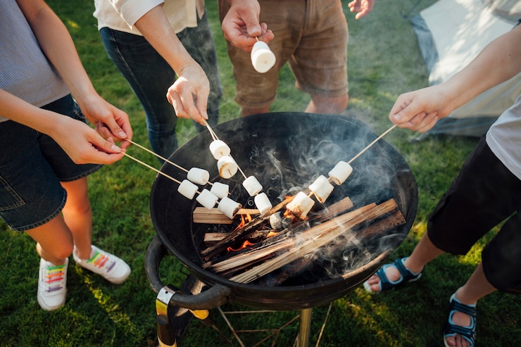 Gratis Foto een verhoogd uitzicht op handen die marshmallows roosteren op een barbecuevuur