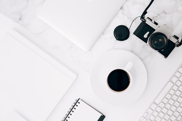 Een verhoogde weergave van het dagboek; digitale tablet; koffiekop; camera en toetsenbord op bureau