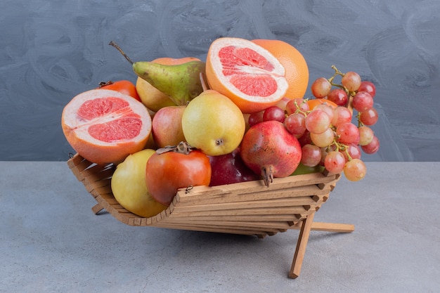 Een verrukkelijk fruitassortiment in een houten mand op marmeren achtergrond.