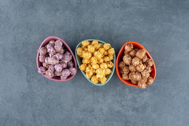 Een verscheidenheid aan popcorn-snoepkleuren, gesorteerd in kleine schaaltjes op marmer