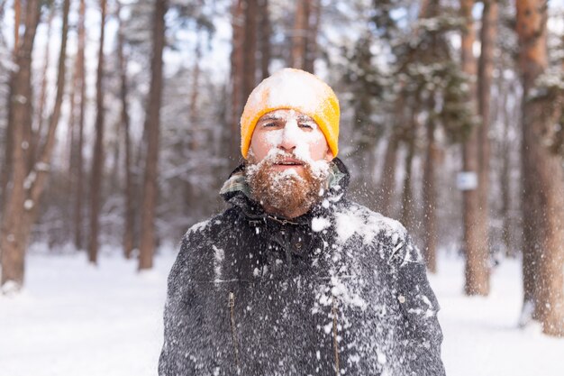Een volwassen man met een baard in een winterbos staat allemaal in de sneeuw, bevroren, ongelukkig met de kou