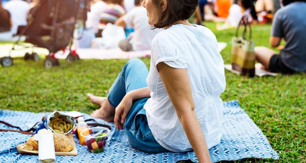Een volwassen vrouw zitten en picknicken in het park