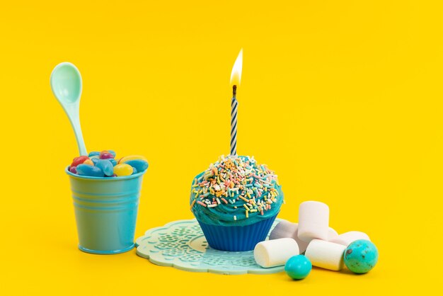 Een vooraanzicht blauwe cake met kaars samen met marshmallows en marmelade op geel, zoet suikerkoekje