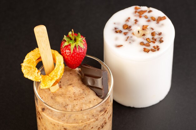 Een vooraanzicht bruin chocodessert smakelijk heerlijk zoet met gemalen koffiechocobar en aardbei geïsoleerd met witte kaars op de donkere achtergrond zoet verfrissend dessert