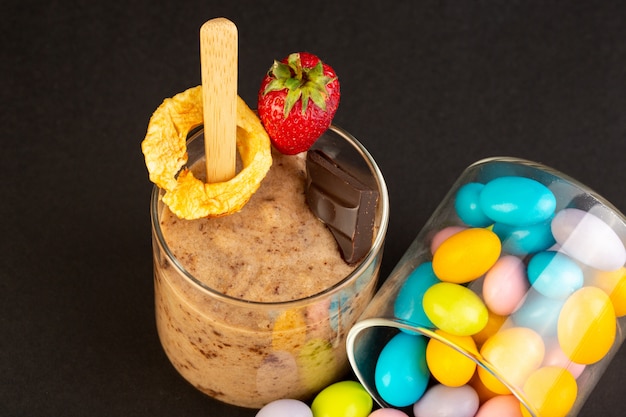 Een vooraanzicht bruin chocodessert smakelijk heerlijk zoet met gemalen koffiechocobar en aardbei met suikergoed op de donkere achtergrond zoet verfrissend dessert