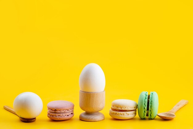 Een vooraanzicht Franse macarons samen met gekookte eieren op geel, het voedsel van het de suikersuikergoed van de koekjescake