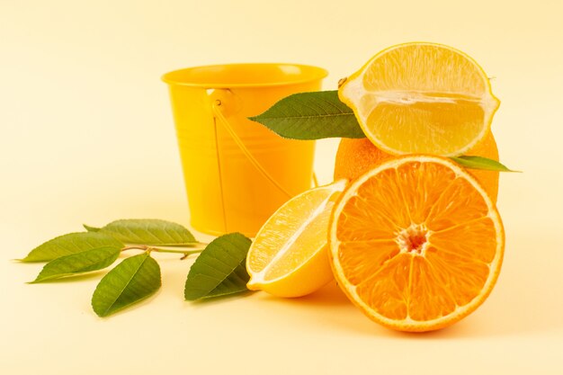 Een vooraanzicht geheel oranje en gesneden stuk samen met gesneden citroen rijpe verse sappige mellow geïsoleerd op de crème achtergrond citrusvruchten sinaasappel