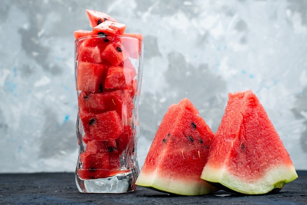 Gratis foto een vooraanzicht gesneden watermeloen zacht en zoet van binnen lang glas op helder bureau