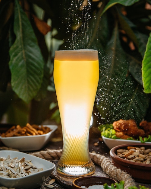 Gratis foto een vooraanzicht iced cocktail in lang glas met gerechten en noten op tafel drink juice cocktail ijs