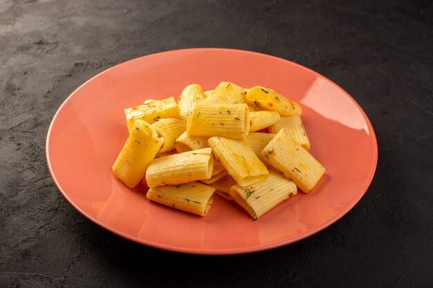 Een vooraanzicht Italiaanse pasta met groene gedroogde kruiden in roze plaat op donker