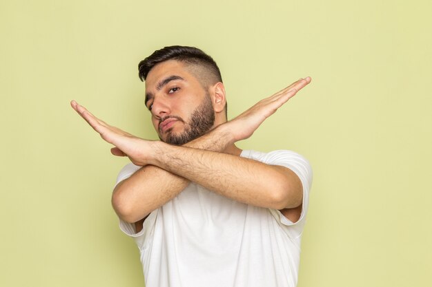 Een vooraanzicht jong mannetje in wit t-shirt dat verbodsteken toont