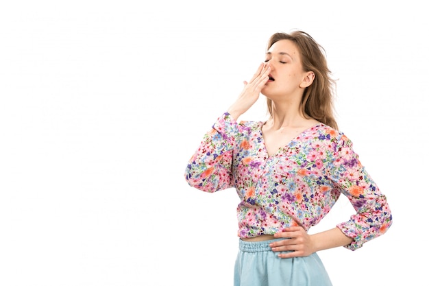 Een vooraanzicht jonge aantrekkelijke dame in kleurrijke bloem ontworpen overhemd en blauwe rok poseren niezen op het wit