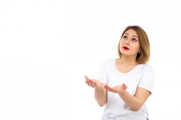 Een vooraanzicht jonge dame in het witte t-shirt stellen die de hemel op het wit onderzoeken