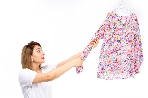 Een vooraanzicht jonge dame in wit overhemd en lichte moderne broek met kleurrijke blouse op de witte