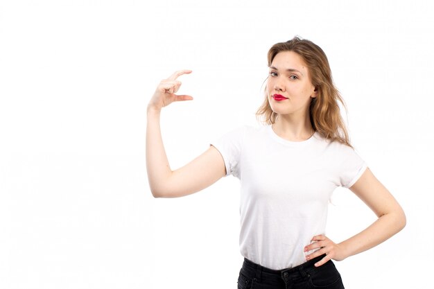 Een vooraanzicht jonge dame in wit overhemd en zwarte moderne jeans met maat op de witte