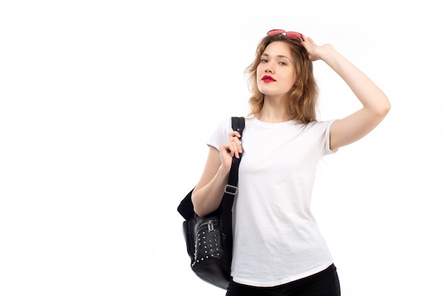 Een vooraanzicht jonge dame in witte t-shirt rode zonnebril zwarte tas op de witte