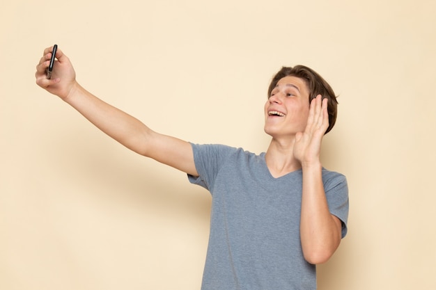 Een vooraanzicht jonge man in grijs t-shirt een selfie te nemen