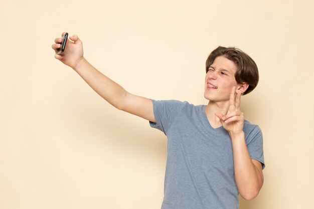 Een vooraanzicht jonge man in grijs t-shirt een selfie te nemen