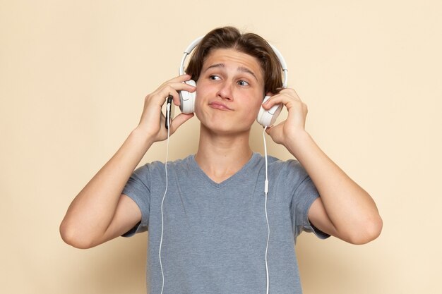 Een vooraanzicht jonge man in grijs t-shirt luisteren naar muziek