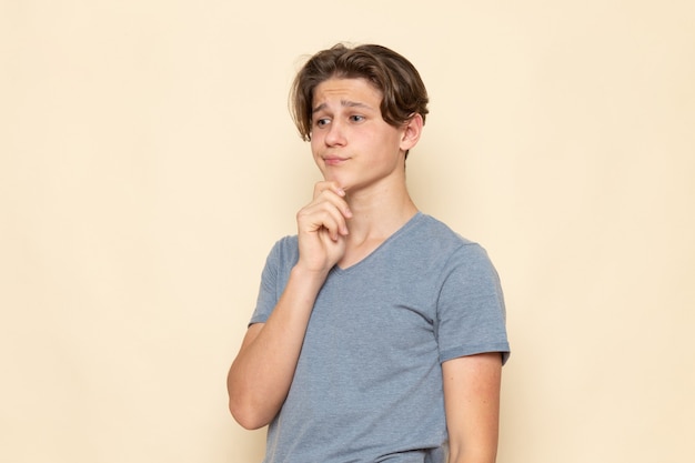 Een vooraanzicht jonge man in grijs t-shirt poseren met denken expressie