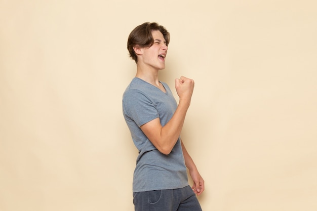 Een vooraanzicht jonge man in grijs t-shirt poseren met opgetogen uitdrukking