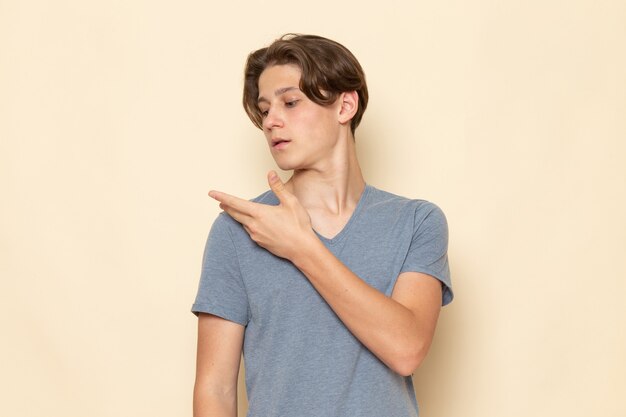 Een vooraanzicht jonge man in grijs t-shirt zijn schouder opruimen