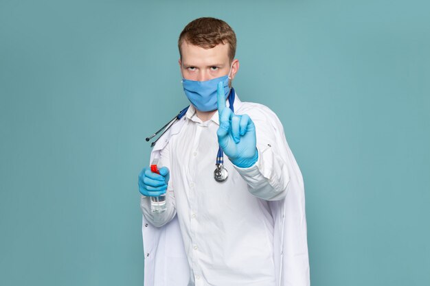 Een vooraanzicht jonge man in wit overhemd en blauwe handschoenen met blauwe masker op de blauwe ruimte