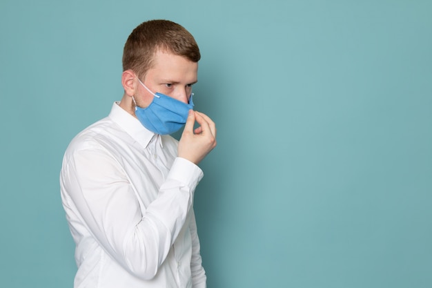 Een vooraanzicht jonge man in wit overhemd en een blauw masker op de blauwe ruimte