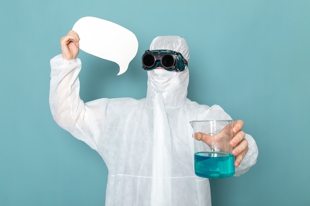 Een vooraanzicht jonge man in wit speciaal pak en met wit bord en oplossing op de blauwe muur man pak gevaar speciale uitrusting kleur