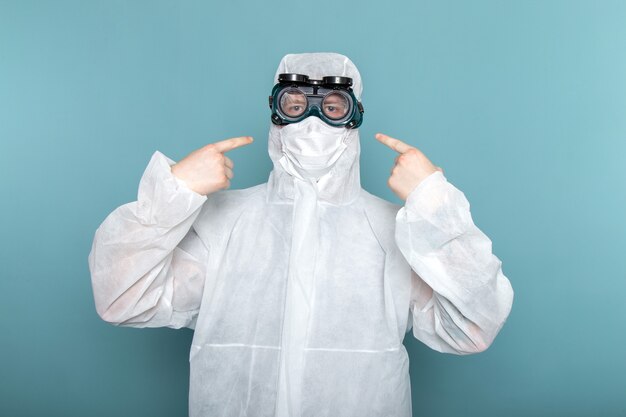 Een vooraanzicht jonge man in wit speciaal pak op de blauwe muur man pak gevaar speciale uitrusting kleur