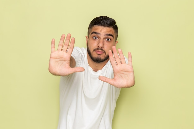 Een vooraanzicht jonge man in wit t-shirt met een bange uitdrukking