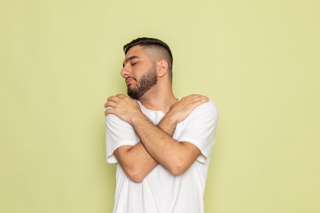 Een vooraanzicht jonge man in wit t-shirt poseren en knuffelen zichzelf