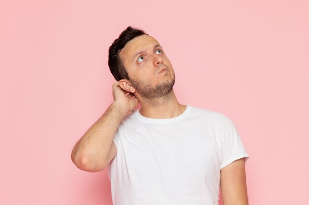 Een vooraanzicht jonge man in wit t-shirt poseren met denken expressie