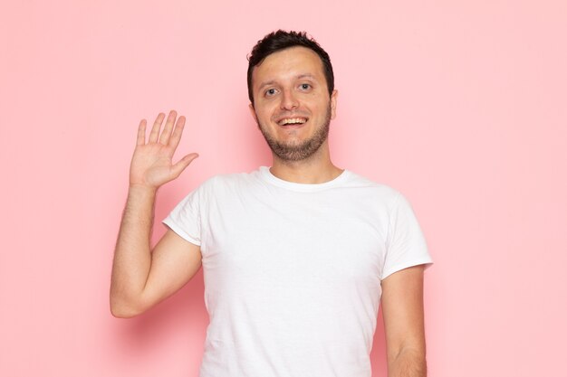 Een vooraanzicht jonge man in wit t-shirt poseren met een glimlach