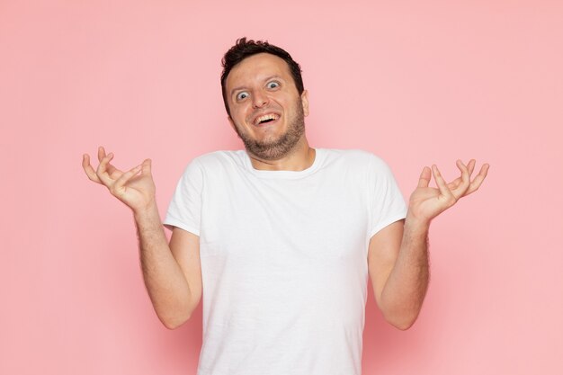 Een vooraanzicht jonge man in wit t-shirt poseren met grappige uitdrukking