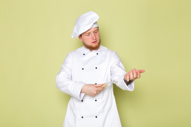 Een vooraanzicht jonge mannelijke kok in wit kokkostuum wit hoofd GLB-holdingsmes