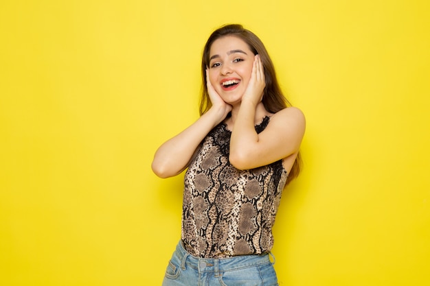 Een vooraanzicht jonge mooie dame in bruine blouse en blauwe jeans glimlachen