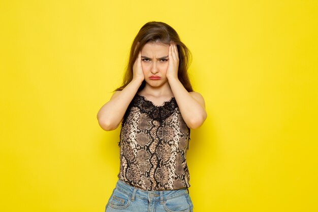 Een vooraanzicht jonge mooie dame in bruine blouse en spijkerbroek benadrukt