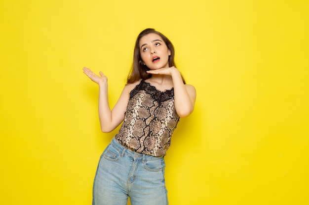 Een vooraanzicht jonge mooie dame in bruine blouse en spijkerbroek poseren