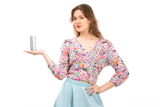 Een vooraanzicht jonge mooie dame in kleurrijke bloem ontworpen shirt en blauwe rok met zilveren blikje drinken op de witte