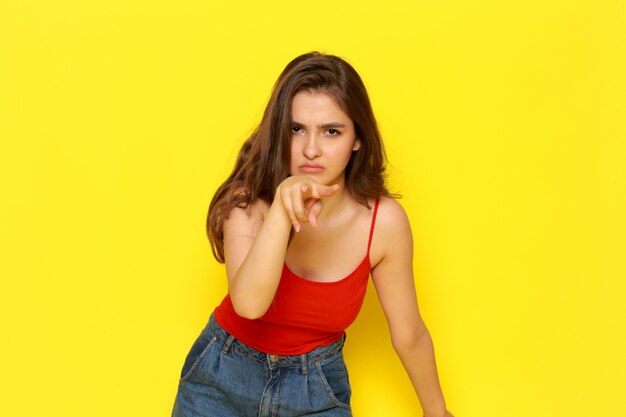 Een vooraanzicht jonge mooie dame in rood shirt en spijkerbroek met boze uitdrukking